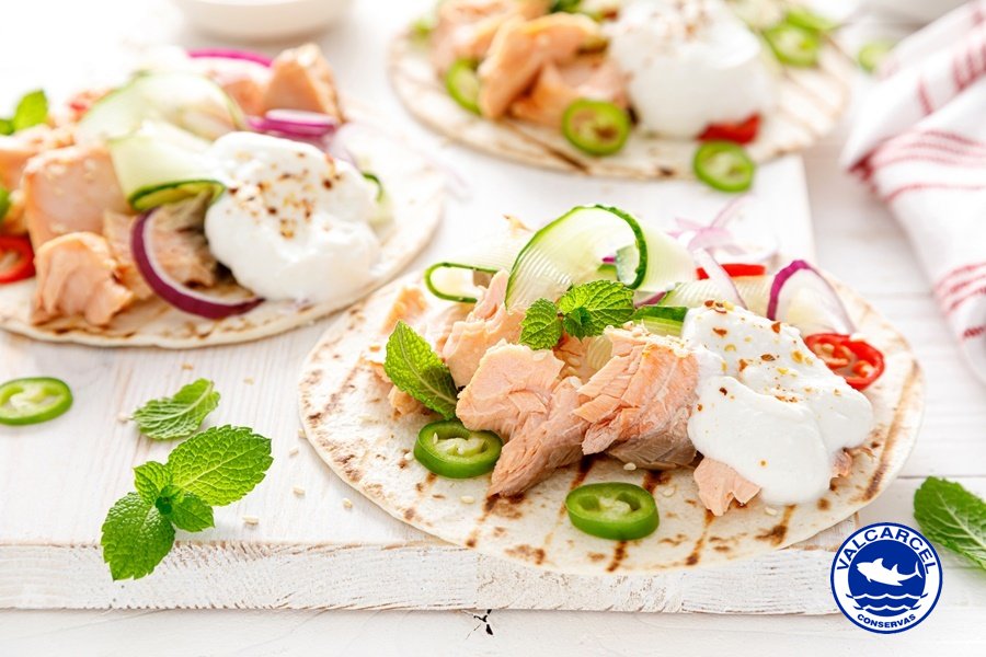 Tacos picantes con salmón al natural, verduras frescas, guindilla, queso ricotta y menta sobre tortillas tostadas, presentados en plato blanco.